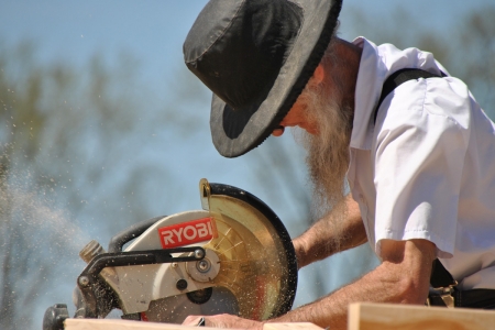 Amish man operating an electric mitre saw