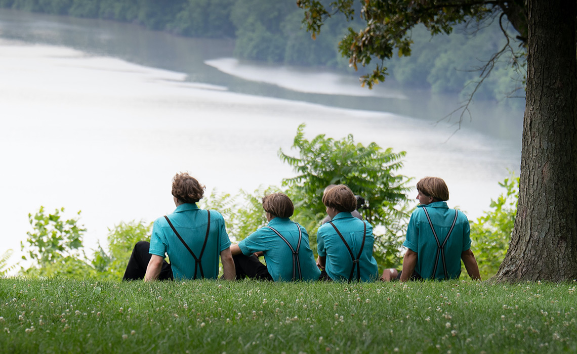 Amish men sitting on the bank of a river