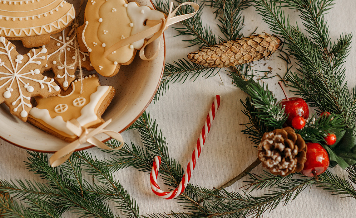 Christmas greens, a plate of cookies, and a candycane on a table