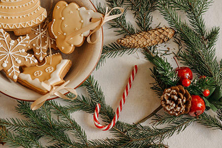 Christmas greens, a plate of cookies, and a candycane on a table